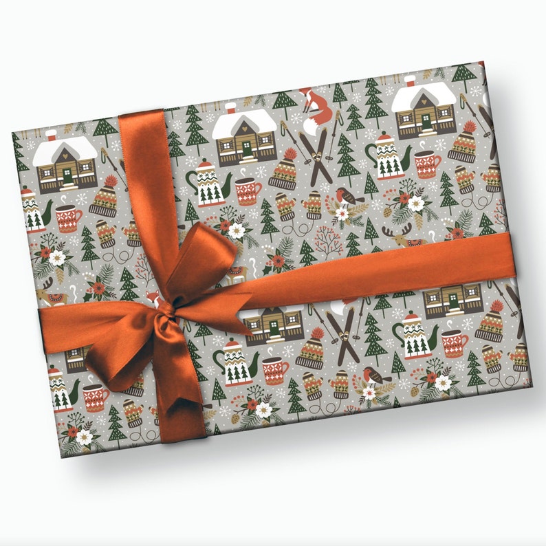 May include: A gray and white gift wrap with a wintery pattern featuring houses, trees, teapots, mugs, and other festive elements. The wrapping paper is tied with a bright orange ribbon.