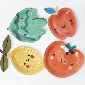 May include: Four colourful paper plates shaped like fruits and vegetables. The plates include a green leaf, a red apple, a yellow lemon, and an orange tomato, each with a smiling face.