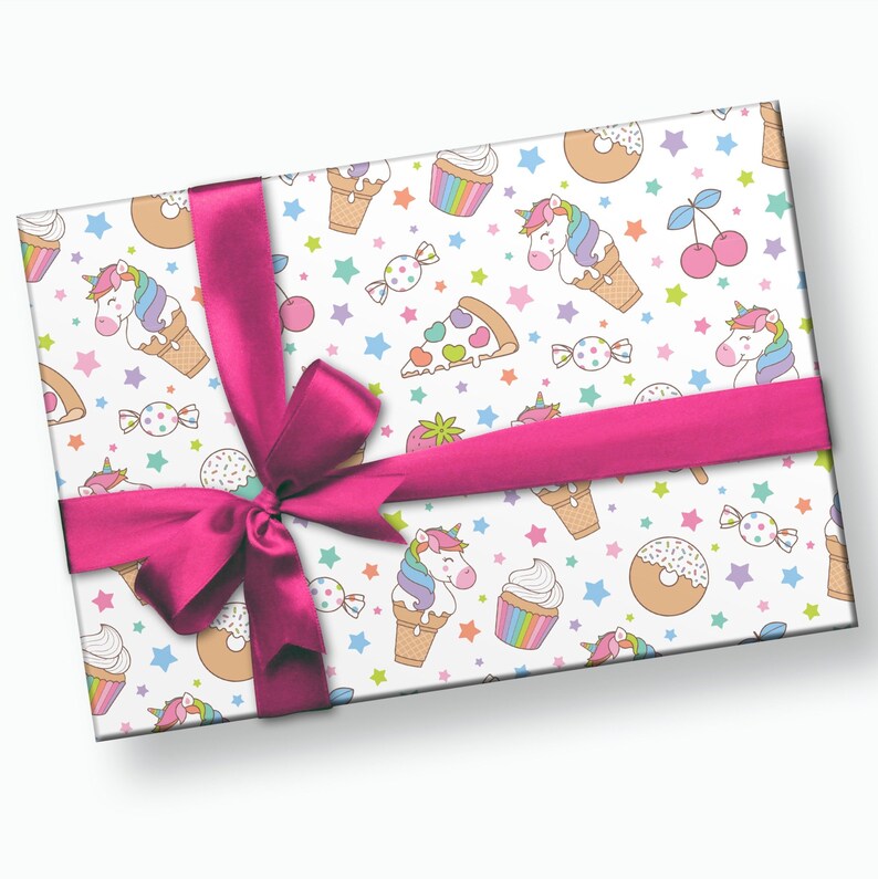 Puede incluir: Papel de regalo blanco con una cinta rosa y un patr&oacute;n repetido de unicornios, conos de helado, donuts, cupcakes, rebanadas de pizza, cerezas, caramelos y estrellas.