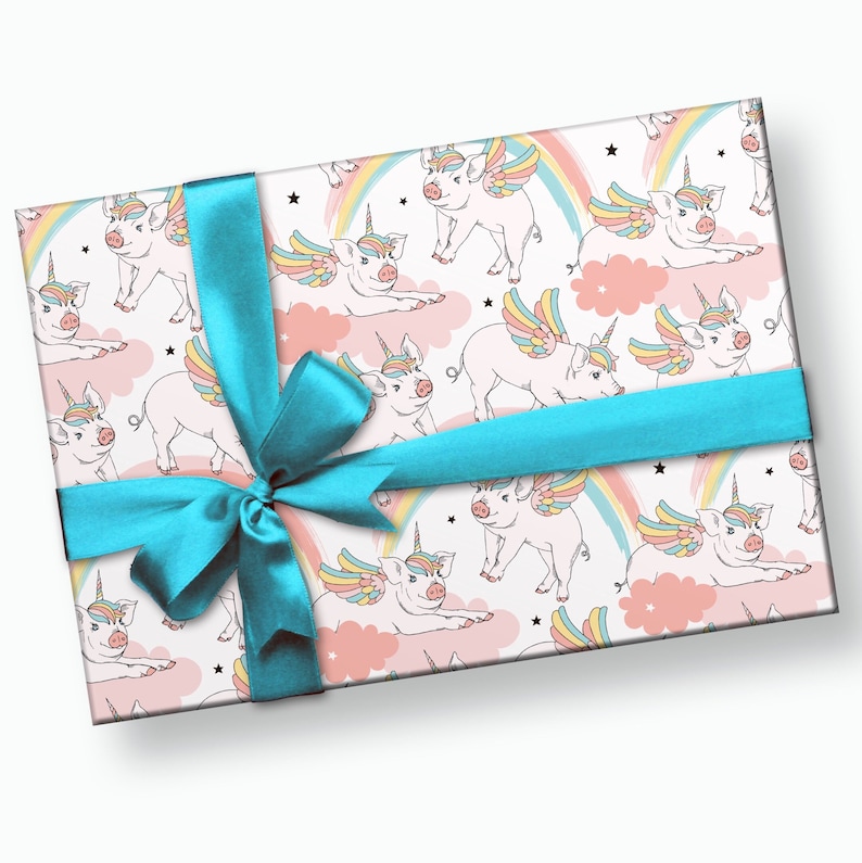 May include: A white gift box with a blue ribbon and a pattern of pink pigs with rainbow wings and unicorn horns on a pink and white background with clouds and stars.