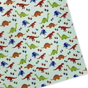 Puede incluir: Un fondo azul claro con un patrón repetido de dinosaurios coloridos. Los dinosaurios son verdes, naranjas, rojos y azules. También hay pequeñas huellas de dinosaurio azules dispersas por todo el patrón.