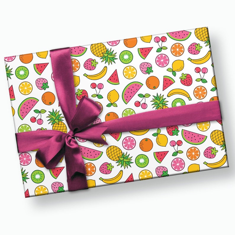 May include: A white gift box with a pink ribbon and a colorful fruit pattern. The pattern includes watermelon, pineapple, bananas, strawberries, lemons, limes, and cherries.