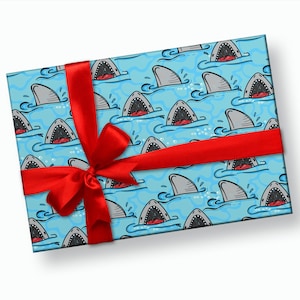 May include: A blue gift wrap with a red ribbon and a pattern of cartoon sharks with open mouths. The sharks are swimming in blue water with white bubbles.