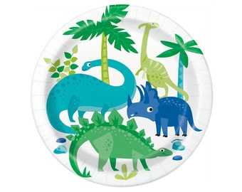 May include: A set of four paper plates featuring a colorful dinosaur design. The plates are white with green palm trees, blue and green dinosaurs, and green leaves.