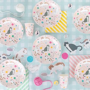 May include: A set of pink and white cat-themed party supplies, including plates, cups, napkins, and decorations. The plates and cups feature a pink background with colorful cats, yarn balls, and mice. The napkins have a pink and white striped pattern. The decorations include cat-shaped cutouts and yarn balls.