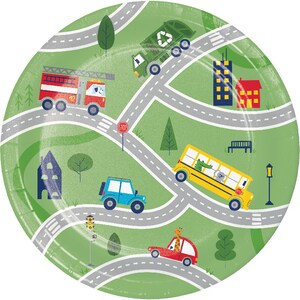 May include: A green paper plate with a city scene featuring a red fire truck, a yellow school bus, a green garbage truck, a blue car, a red car, and a stop sign. The plate has a white border with a dashed line pattern.