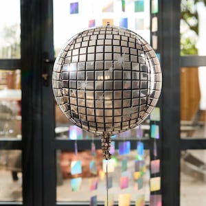 May include: A silver disco ball balloon with a mirrored surface and white star-shaped designs.