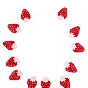 K&ouml;nnte beinhalten: Eine Girlande aus roten und rosafarbenen Erdbeeren mit wei&szlig;em Band. Die Girlande ist aus Filz und hat ein schlichtes Design.