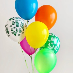 Puede incluir: Un grupo de seis globos, que incluyen un globo azul, un globo naranja, un globo amarillo, un globo rosa, un globo verde y un globo blanco con un patr&oacute;n de cactus verde.