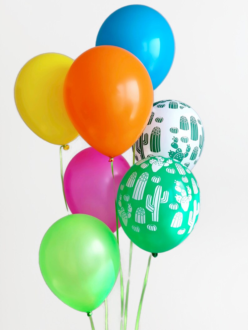 Puede incluir: Un mont&oacute;n de globos de colores, incluyendo verde, amarillo, naranja, rosa y azul, con un globo que presenta un patr&oacute;n de cactus blanco sobre un fondo verde.
