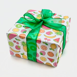 May include: A white gift box with a green ribbon and a colorful fruit pattern. The pattern includes watermelon, strawberries, pineapples, lemons, limes, and kiwi.