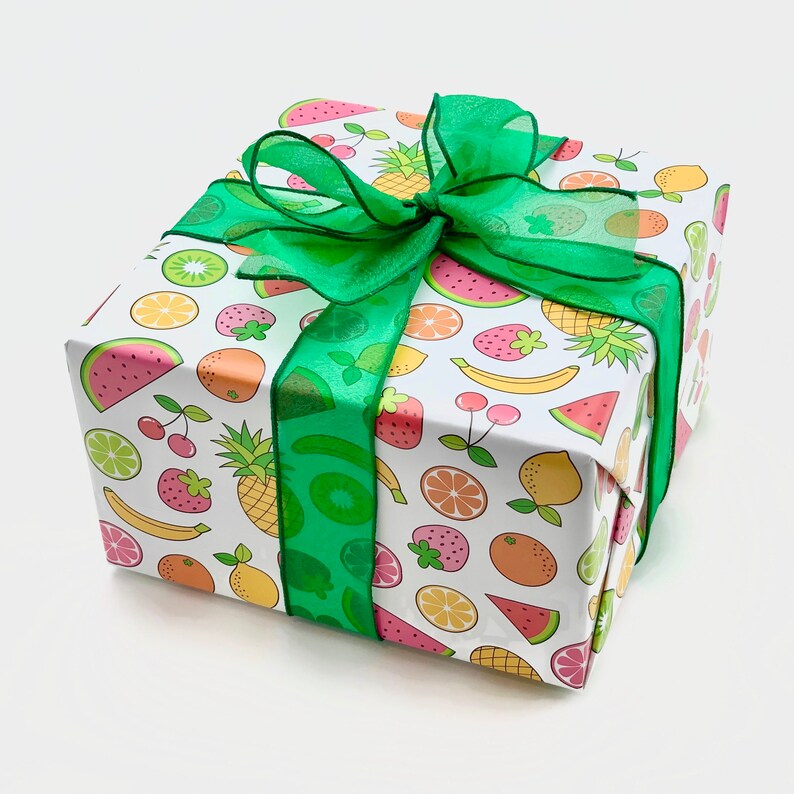 May include: A white gift box with a green ribbon and a colorful fruit pattern. The pattern includes watermelon, strawberries, pineapples, lemons, limes, and kiwi.