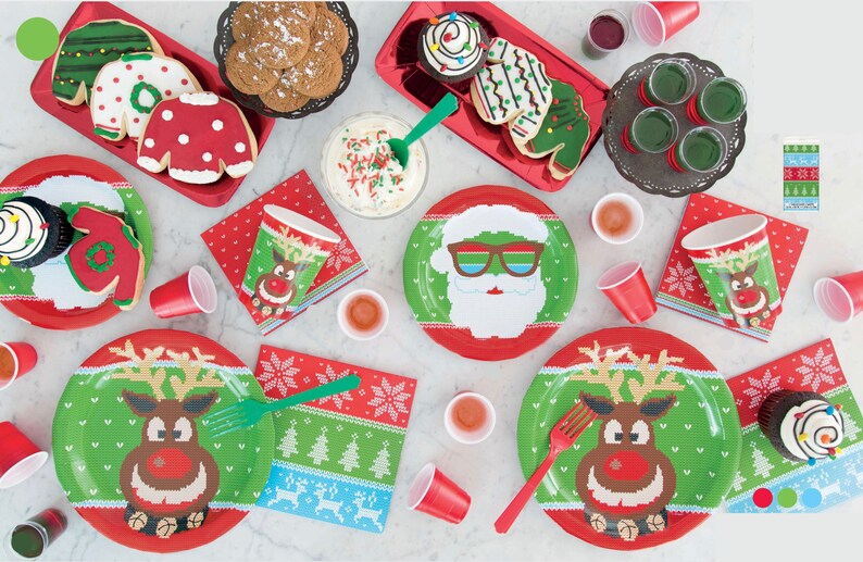 Pu&ograve; includere: Una tavola imbandita per una festa di Natale con piatti, bicchieri e tovaglioli di carta rossi e verdi con un renna e Babbo Natale in un design di maglione festivo. Ci sono anche biscotti e cupcake decorati con luci natalizie e una ghirlanda.