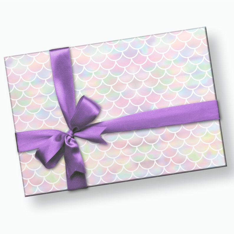 May include: A gift box wrapped in iridescent mermaid scale patterned paper with a purple satin ribbon tied in a bow.