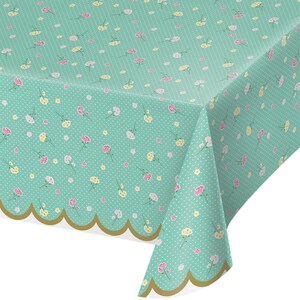 May include: A teal tablecloth with a scalloped gold border. The tablecloth has a repeating pattern of small white dots and pink and yellow flowers.