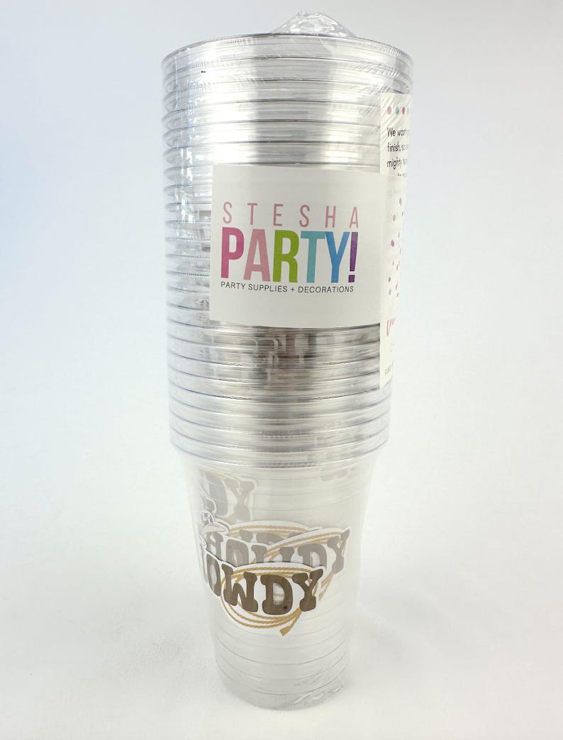 Puede incluir: Una pila de vasos de fiesta de pl&aacute;stico transparente envueltos en pl&aacute;stico. Las tazas tienen un dise&ntilde;o "Howdy" en marr&oacute;n y dorado. Una etiqueta en el embalaje dice "STESHA PARTY! PARTY SUPPLIES + DECORATIONS."