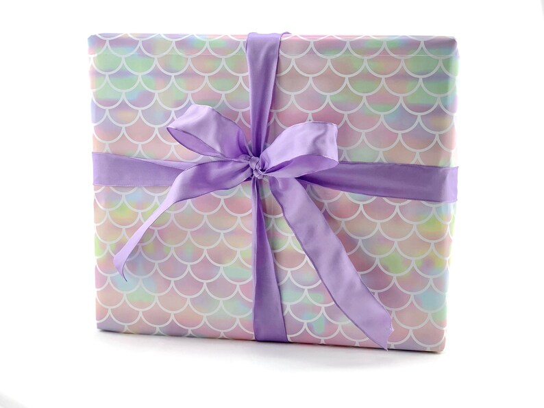 May include: A gift box wrapped in iridescent mermaid scale patterned paper with a large purple satin bow.