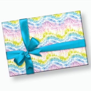 May include: A gift box wrapped in colorful tie-dye patterned paper with a bright blue ribbon tied in a bow.