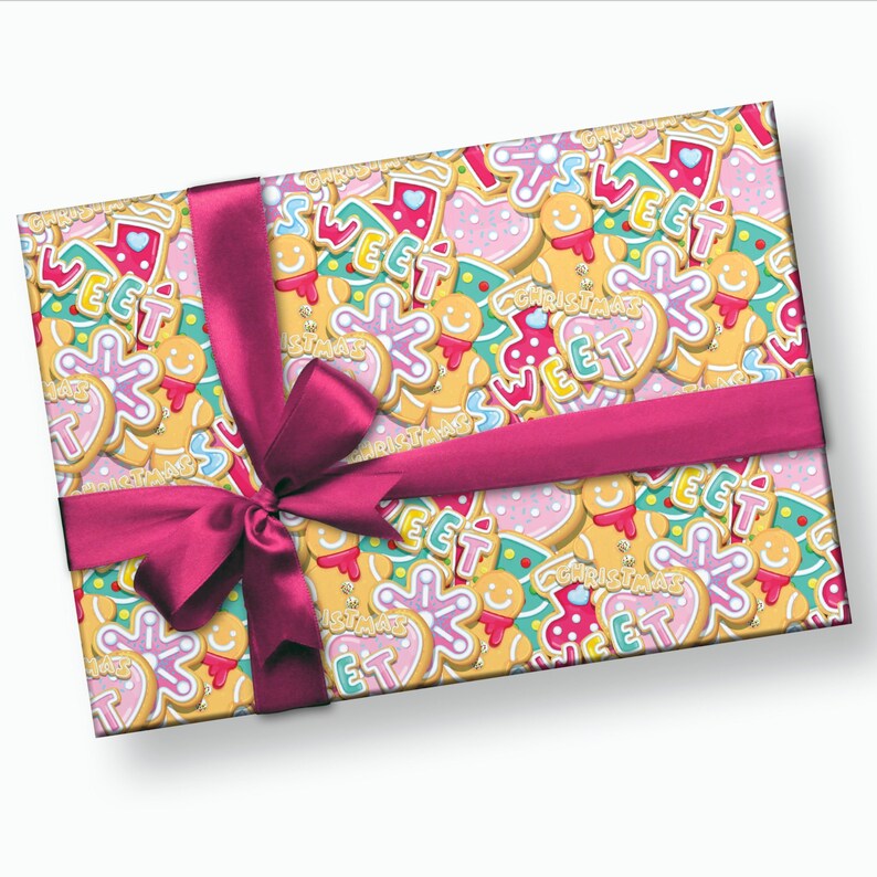 May include: A pink and white gift box with a pink ribbon and bow. The box is wrapped in paper with a pattern of gingerbread cookies with the words "Sweet" and "Christmas" on them.