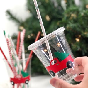 K&ouml;nnte beinhalten: Zwei durchsichtige Plastikbecher mit roten Lastwagen-Weihnachtsbaum-Designs. Die Becher haben rot-wei&szlig; gestreifte Strohhalme.