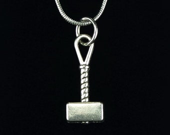 May include: A silver necklace with a small hammer pendant. The necklace is displayed on a black velvet pouch.