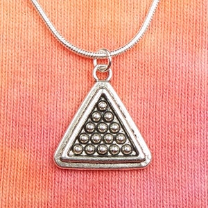 May include: A silver necklace with a triangle pendant featuring a pattern of small silver balls. The pendant is on a silver chain.