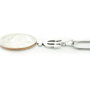 Puede incluir: Collar de plata con un colgante de tridente y una cadena de plata. El colgante es aproximadamente del tama&ntilde;o de una moneda de veinticinco centavos.