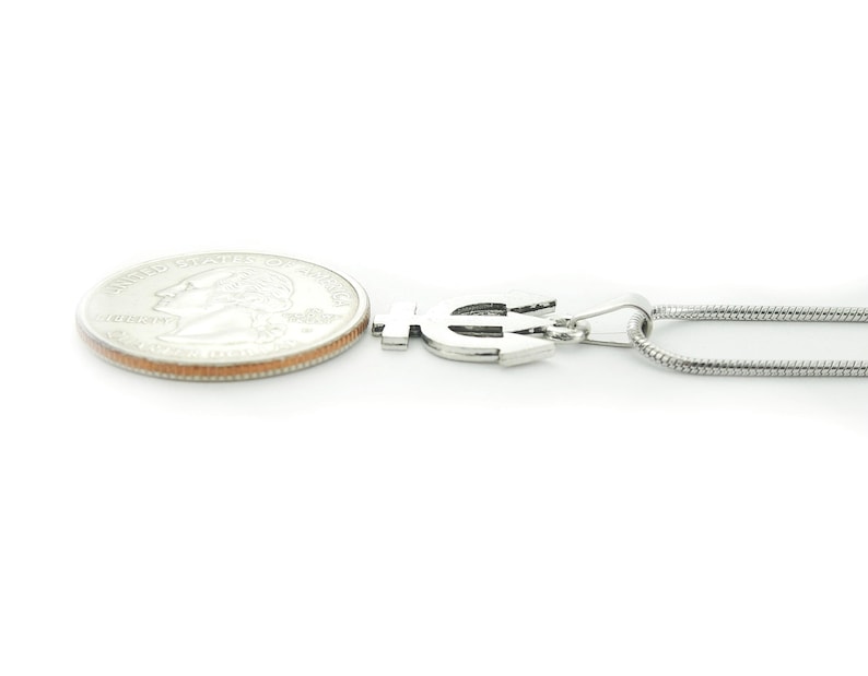 Puede incluir: Collar de plata con un colgante de tridente y una cadena de plata. El colgante es aproximadamente del tama&ntilde;o de una moneda de veinticinco centavos.
