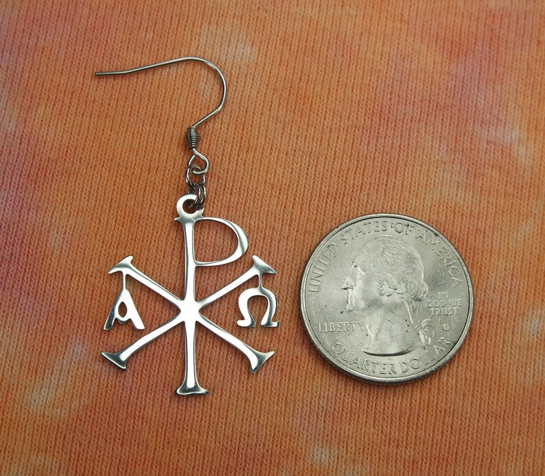 May include: Silver earring with a Chi Rho symbol, a Christian symbol that represents the first two letters of Christ's name in Greek, with the letters Alpha and Omega on either side. The earring is about the size of a quarter.