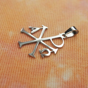 May include: Silver pendant with a stylized cross and the letters 'XP' inscribed on it.