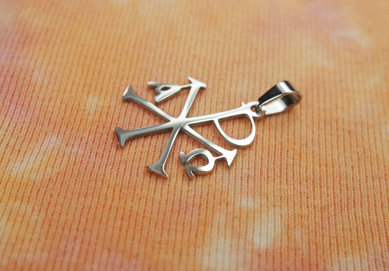 May include: Silver pendant with a stylized cross and the letters 'XP' inscribed on it.