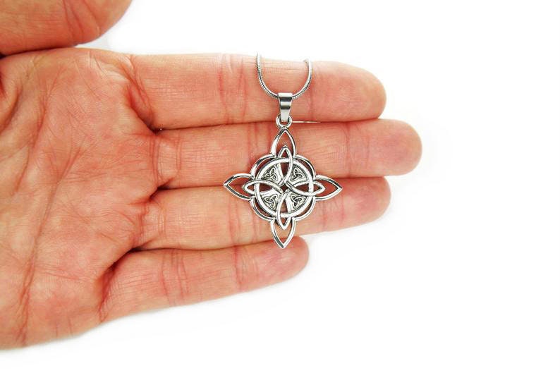 May include: A silver Celtic knot pendant necklace with a four-pointed star design. The pendant is intricate and detailed, with a smooth, polished finish.