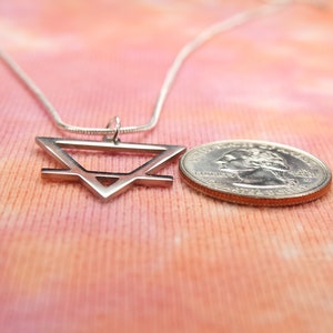 May include: A silver necklace with a geometric pendant in the shape of a triangle. The pendant is about the size of a quarter.