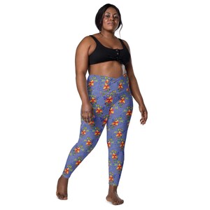 May include: Blue leggings with a floral pattern featuring red and yellow flowers and green leaves. The leggings have a high waist and a pocket on each side. The model is wearing a black sports bra.