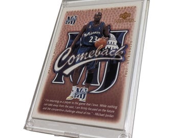 May include: A Michael Jordan "Comeback" Upper Deck trading card in a protective case. The card shows Jordan in a Washington Wizards uniform, holding a basketball. Text includes "Comeback" and a quote by Michael Jordan.