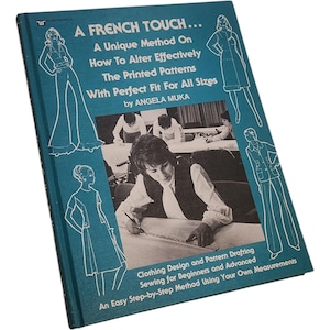 May include: A vintage book titled "A French Touch..." with a teal cover. The book's cover features illustrations of fashion designs and text about altering patterns for all sizes. The book is about clothing design and pattern drafting.