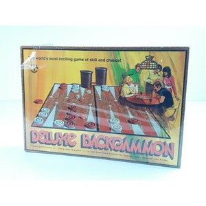 May include: A vintage box for a Deluxe Backgammon game. The box features a colorful illustration of people playing the game, with a game board, dice, and cups. The text on the box reads "The world's most exciting game of skill and chance!" and "Deluxe Backgammon".