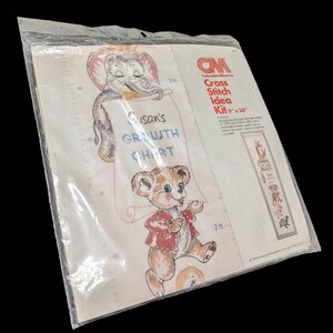Puede incluir: Un kit de punto de cruz con una tabla de crecimiento con un elefante y un oso sosteniendo rollos. El kit incluye tela 100% algodón, hilo de bordar e instrucciones. El kit mide 23 cm por 97 cm.