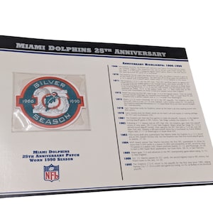 May include: A white card with a blue and green patch featuring a dolphin and the text "Silver 25th Season 1966-1990". The card also includes a list of Miami Dolphins 25th Anniversary Highlights from 1966-1990.