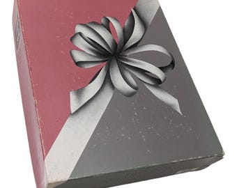 May include: A pink and silver gift box with a white bow. The bow is tied in a knot and the ends of the ribbon are hanging down.