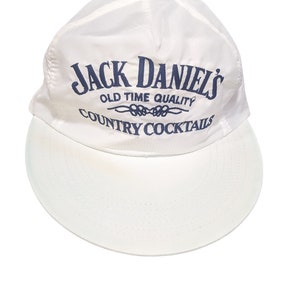 以下が含まれることがあります： 「Jack Daniel's Old Time Quality Country Cocktails」と刺繍された青いロゴが付いた白い野球帽。
