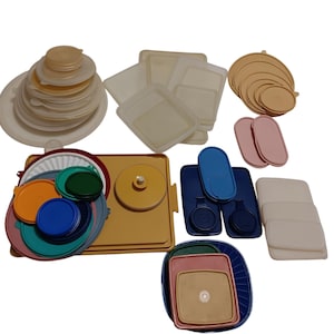 Puede incluir: Una colección de tapas y recipientes de plástico para guardar alimentos en varios colores. Las tapas son en tonos blanco, beige, azul, rosa, naranja y verde. Los recipientes son cuadrados, redondos y ovalados.