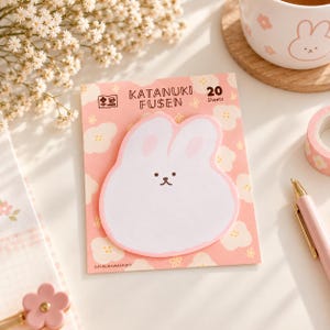 May include: A pack of 20 Katanuki Fusen sticky notes featuring a white rabbit-shaped memo pad on a pink backing card with a white floral pattern. The text reads Katanuki Fusen and 20 Sheets. The rabbit has pink inner ears and a simple face.