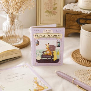 May include: A rectangular pack of sticky notes with a light purple cover featuring the text A Rabbit With a Floral Ornament and an illustration of a rabbit sitting in a chair. The pack contains 40 sheets and displays a decorative border.