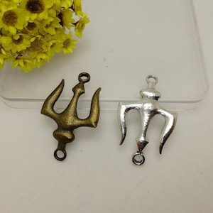 Op de afbeelding: Twee drietand bedels, een in antiek goud en een in zilver, met een lus aan de bovenkant om te bevestigen aan sieraden of andere knutselwerkjes.