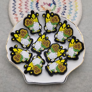 May include: A collection of ten yellow and black gnome figurines with sunflowers. Each gnome is wearing a yellow crown and holding a sunflower.