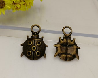 May include: Two antique bronze ladybug charms with a loop for attaching to jewelry or crafts. The ladybug on the left has black spots and the ladybug on the right is a solid bronze color.