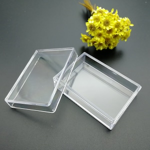 May include: Two clear plastic rectangular boxes, one slightly larger than the other, are stacked on top of each other. The boxes are empty and have a smooth, glossy finish.