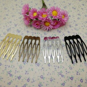 Pode incluir: Uma coleção de pentes de cabelo em dourado, bronze, prateado e preto. Cada pente tem uma série de dentes curvos. Um buquê de flores artificiais rosa e amarelas ao fundo. Estes pentes são adequados para vários penteados.