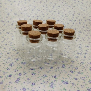 May include: Ten small glass bottles with cork stoppers. The bottles are clear and the corks are brown.